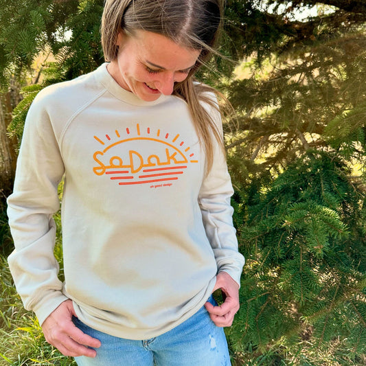 Person wearing a beige sweatshirt with a logo outdoors