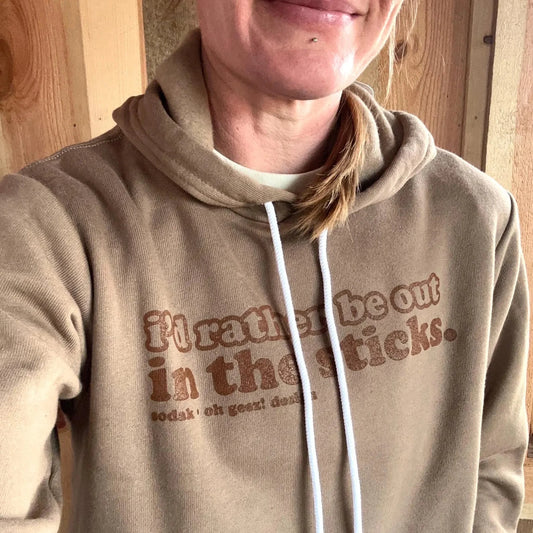 Person wearing a beige hoodie with text in front of a wooden wall.
